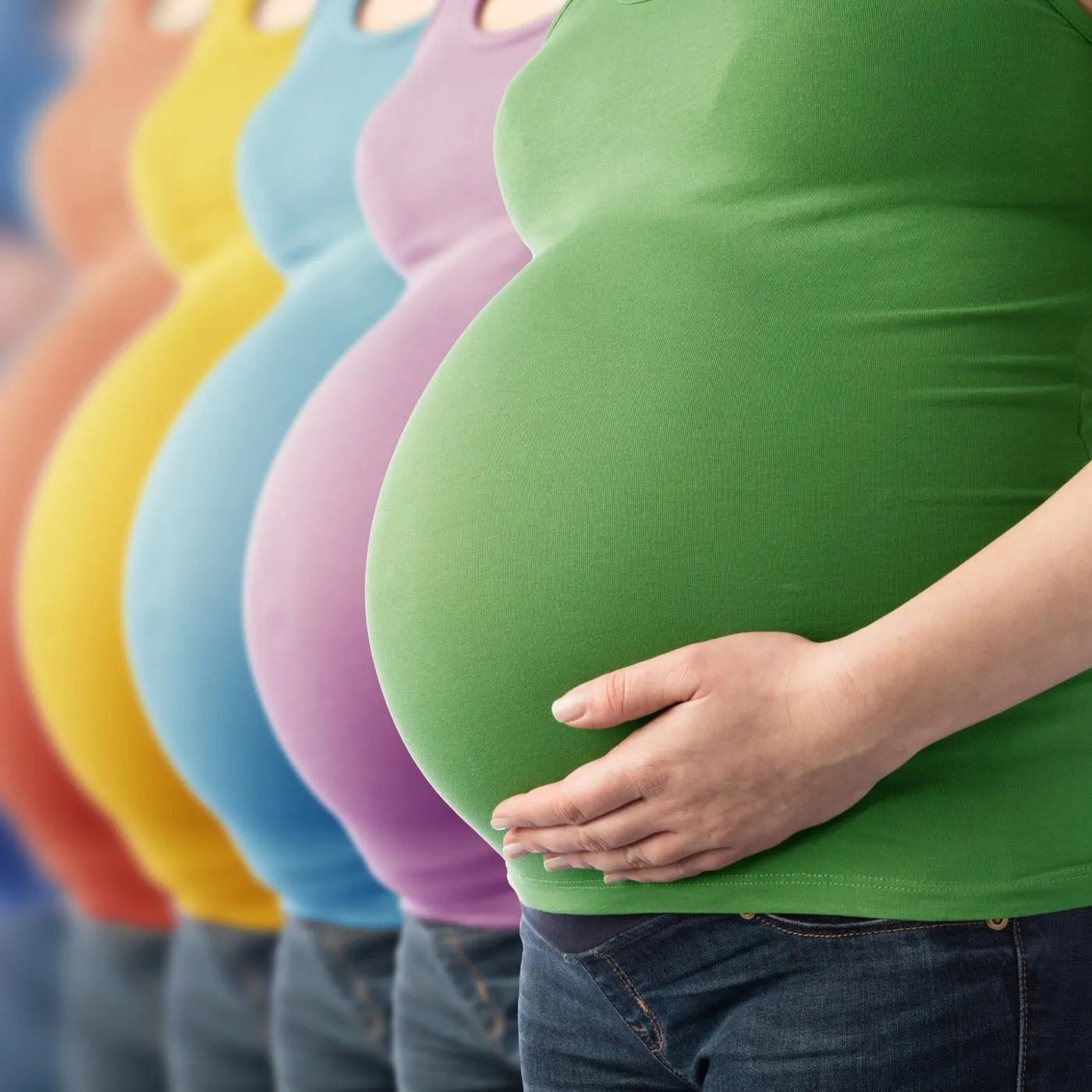 Mehrere schwangere Frauen in bunten Oberteilen stehen hintereinander, die vordere legt eine Hand auf ihren Bauch